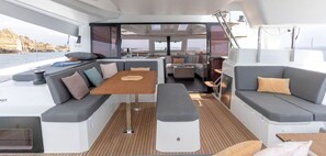 Ein modernes Bootsinnere mit Essbereich, Sitzgelegenheiten und Blick aufs Wasser.