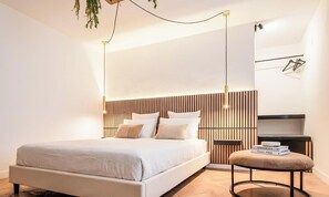 Ein modernes Schlafzimmer mit einem Bett, Nachttischen, einer hängenden Pflanze und einem kleinen runden Tisch mit Büchern.