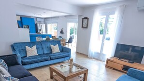 A modern living room with a blue sofa, a coffee table, and a TV stand. - Porte Bleue - perfect for group holidays or wedding guests (Eymet)