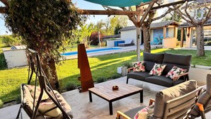 A patio with outdoor furniture, a swing chair, and a view of a swimming pool and garden. - Porte Bleue - perfect for group holidays or wedding guests (Eymet)