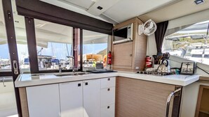 A compact kitchen with white cabinets, a microwave, and a small stove. - Sun-Kissed Sailing: A Caribbean Beach Experience from Islas Vírgenes de Estados Unidos, Santo Tomás (St Thomas)
