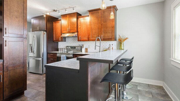 A modern kitchen with wooden cabinets, stainless steel appliances, and a central island with bar stools.