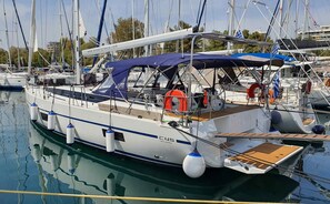A sailboat docked at a marina with a covered deck, life rings, and a wooden deck. - Sun-Kissed Sailing Adventure in Islas Sarónicas (Alimos)