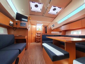 A compact interior with a kitchenette, seating area, and multiple windows. - Sun-Kissed Sailing Adventure in Islas Sarónicas (Alimos)