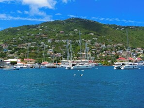 Uma marina com barcos atracados, uma colina com edifícios e céu azul límpido.