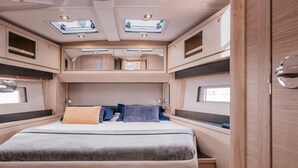 Een goed verlicht RV-interieur met een stapelbed, een laag bed en een kleine zithoek.