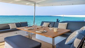 Ein Essbereich mit Tisch für zwei Personen, einer gepolsterten Sitzecke und Blick aufs Meer.