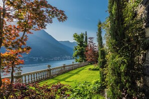 Un jardín con un cuerpo de agua, montañas y un muro de piedra.