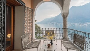 A balcony with two chairs, a table with a vase, and a view of a lake and mountains. - Villa Madonnina (Pognana Lario)