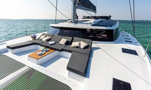 A yacht with a sun lounge area, a dining table, and a view of the sea. - Caribbean Dream: Sun-soaked Sailing Adventure from Tortola, Islas Vírgenes Británicas (Road Town)
