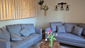 A living room with two grey sofas, a wooden coffee table, a woven rug, and a wooden slat partition. - Beautifully renovated family home (Saint-Romain)