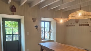 A room with a wooden bench, a table, a door with a window, and a hanging light fixture. - Beautifully renovated family home (Saint-Romain)