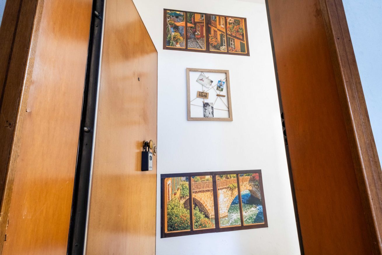 Een muur met ingelijste foto's, een deur en een houten constructie.