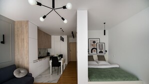 Un espacio habitable moderno y funcional con kitchenette, comedor y cama.