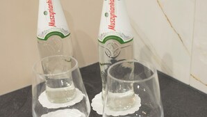 Dos botellas de cerveza Muszynka, dos vasos y dos barras de chocolate Mars sobre una superficie oscura.