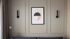 Una habitación con una cama, una obra de arte abstracta enmarcada y lámparas fijadas a la pared.
