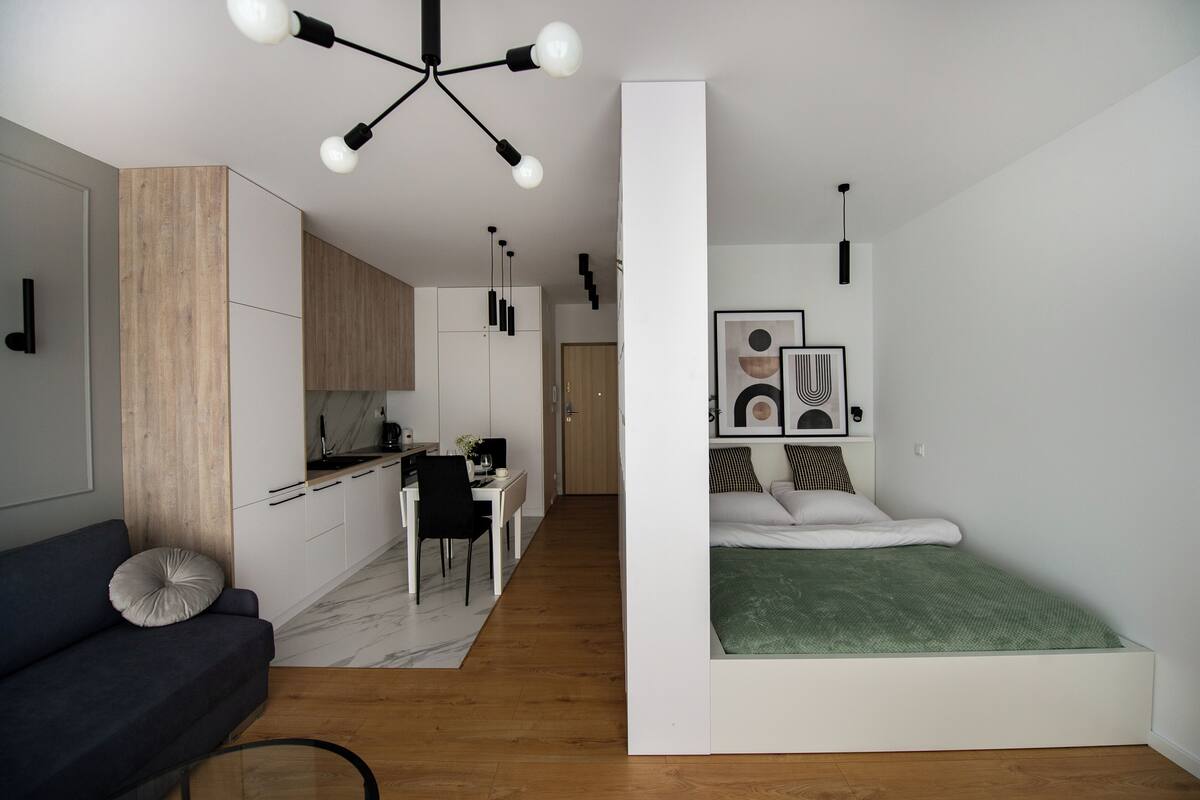 Ein kompakter Wohnbereich mit Küchenzeile, Essplatz, Bett und Schlafsofa.