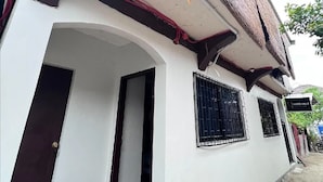 Ein weißes Gebäude mit einer roten Tür, einem Fenster mit Metallgitter und einem Schild, auf dem 'HAIDO VILLE' steht.