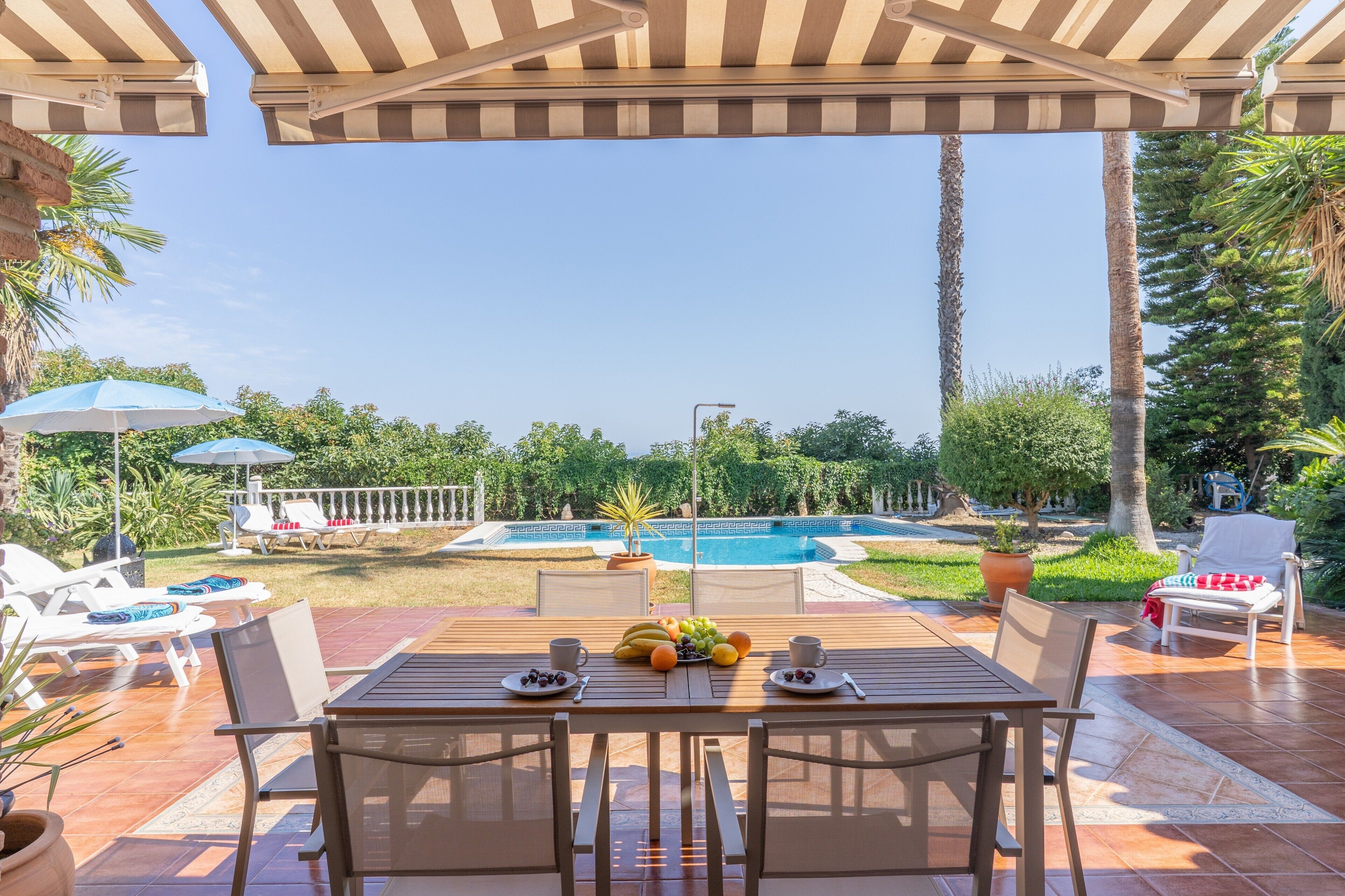 Eine Terrasse mit Tisch für Zwei, einem Pool und Liegestühlen.