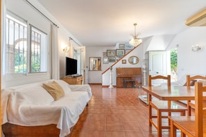 A spacious living area with a sofa, dining table, and chairs, a fireplace, and a staircase leading to another level. - Country House 'Villa Miramar' with Sea View, Wi-Fi and Air Conditioning (Algarrobo)