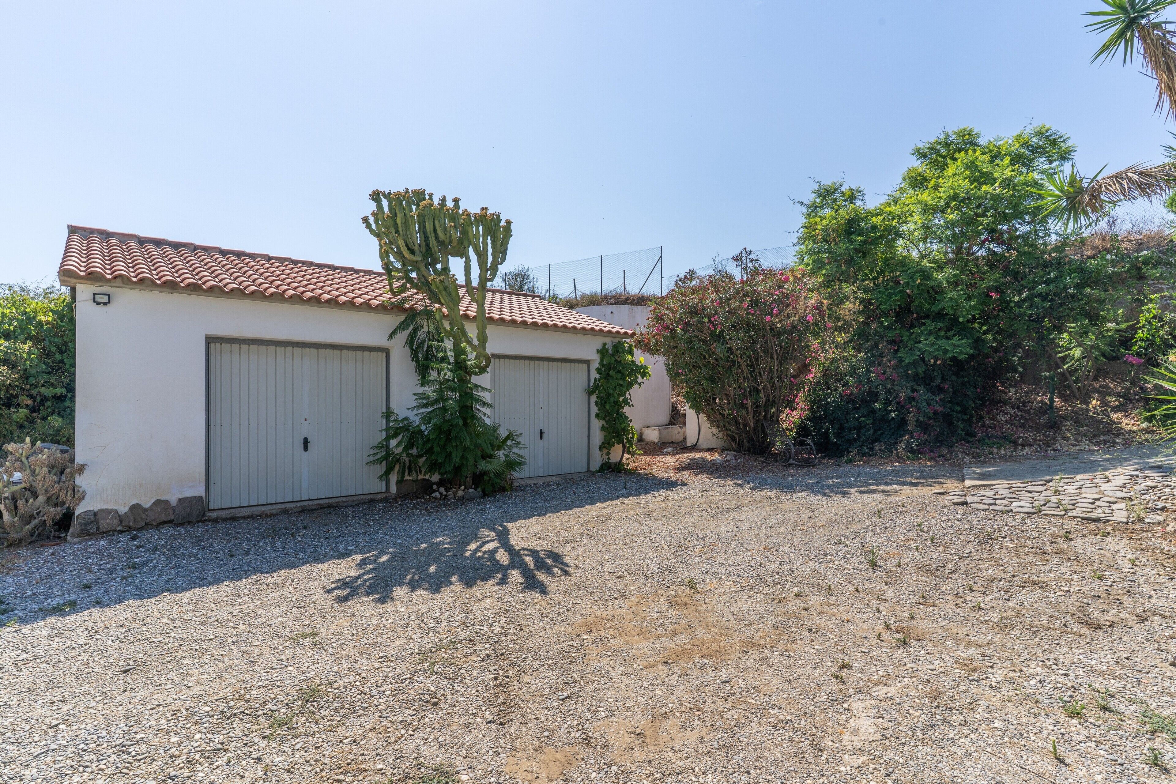 A building with a tiled roof, a garage door, and a gravel driveway.