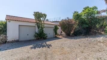 A building with a tiled roof, a garage door, and a gravel driveway.