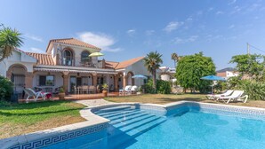 Ein Haus mit Swimmingpool, Gartenmöbeln und Palmen.