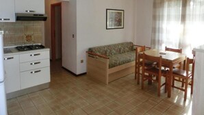 Cucina compatta con piano cottura, pensili e zona pranzo con tavolo e sedie.