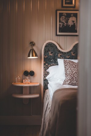 Un dormitorio con una cama, una mesita de noche con una lámpara y un cuadro en la pared.