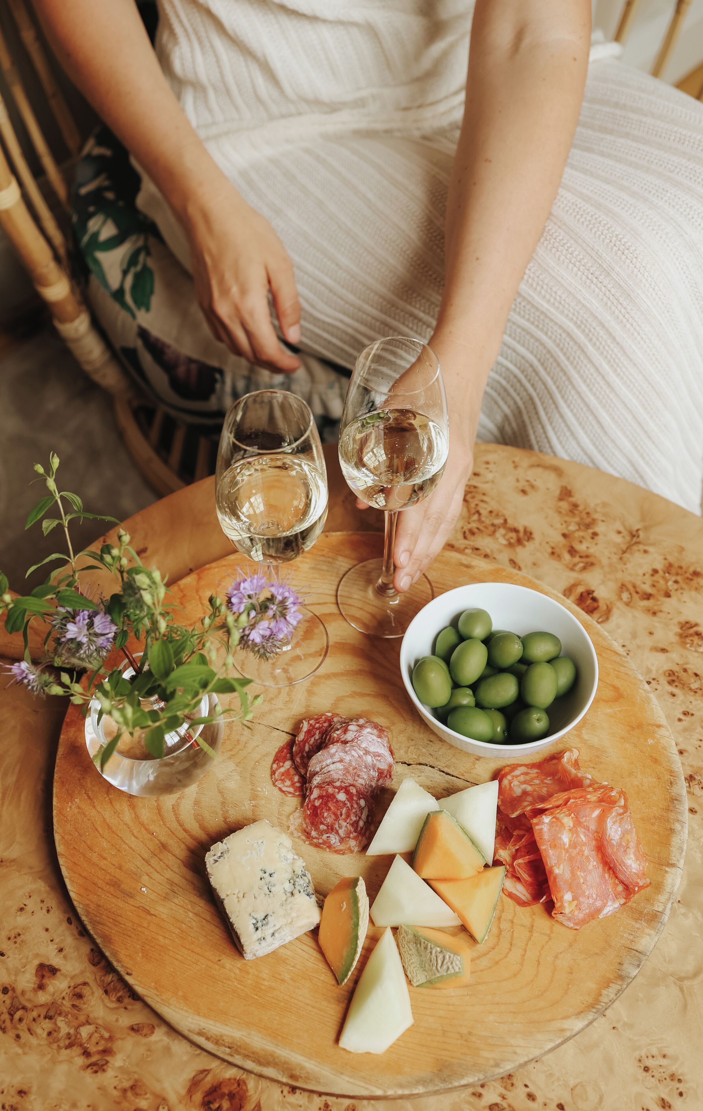 A wooden table with a cheese platter, olives, and sliced meats.
