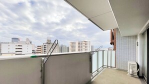 Ein Balkon mit Blick auf Stadtgebäude, einem Metallgeländer und einer gefliesten Wand.