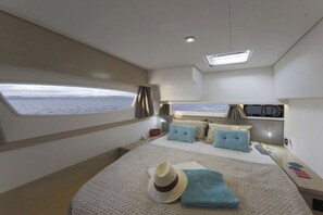 A bedroom with a bed, a window with a view of the sea, a desk, and a small table. - Caribbean Dream: Sun-soaked Sailing Adventure from Tortola, Islas Vírgenes Británicas (Road Town)