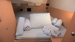 A compact, well-lit cabin with a single bed, a small storage compartment, and a door. - Caribbean Dream: Sun-soaked Sailing Adventure from Tortola, Islas Vírgenes Británicas (Road Town)