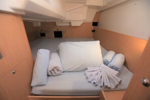 Ein gemütliches, gut beleachtetes Kabinett mit einem Einzelbett, einem kleinen Staufach und einer Tür.