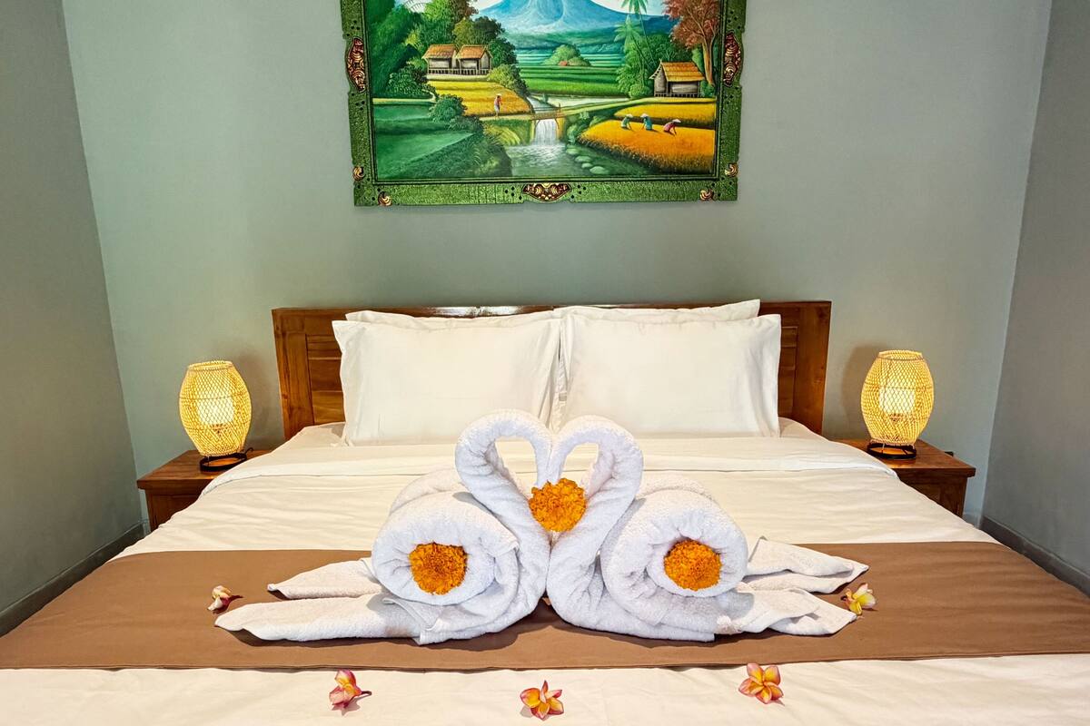 A hotel room with a bed, two nightstands, a painting, and two lamps.