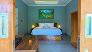 Quarto com cama, duas luminárias de cabeceira, um quadro na parede e uma mesa de madeira com um vaso de flores.