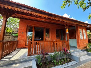 A wooden building with a balcony, a staircase, and a garden area. - Nusa House Ubud By Reccoma (Ubud)