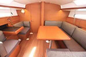A compact interior with a central table, cushioned seating, and a door. - Caribbean Dream: Sun-soaked Sailing Adventure from Tortola, Islas Vírgenes Británicas (Road Town)