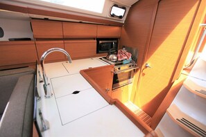 A compact kitchenette with a sink, stove, and microwave. - Caribbean Dream: Sun-soaked Sailing Adventure from Tortola, Islas Vírgenes Británicas (Road Town)