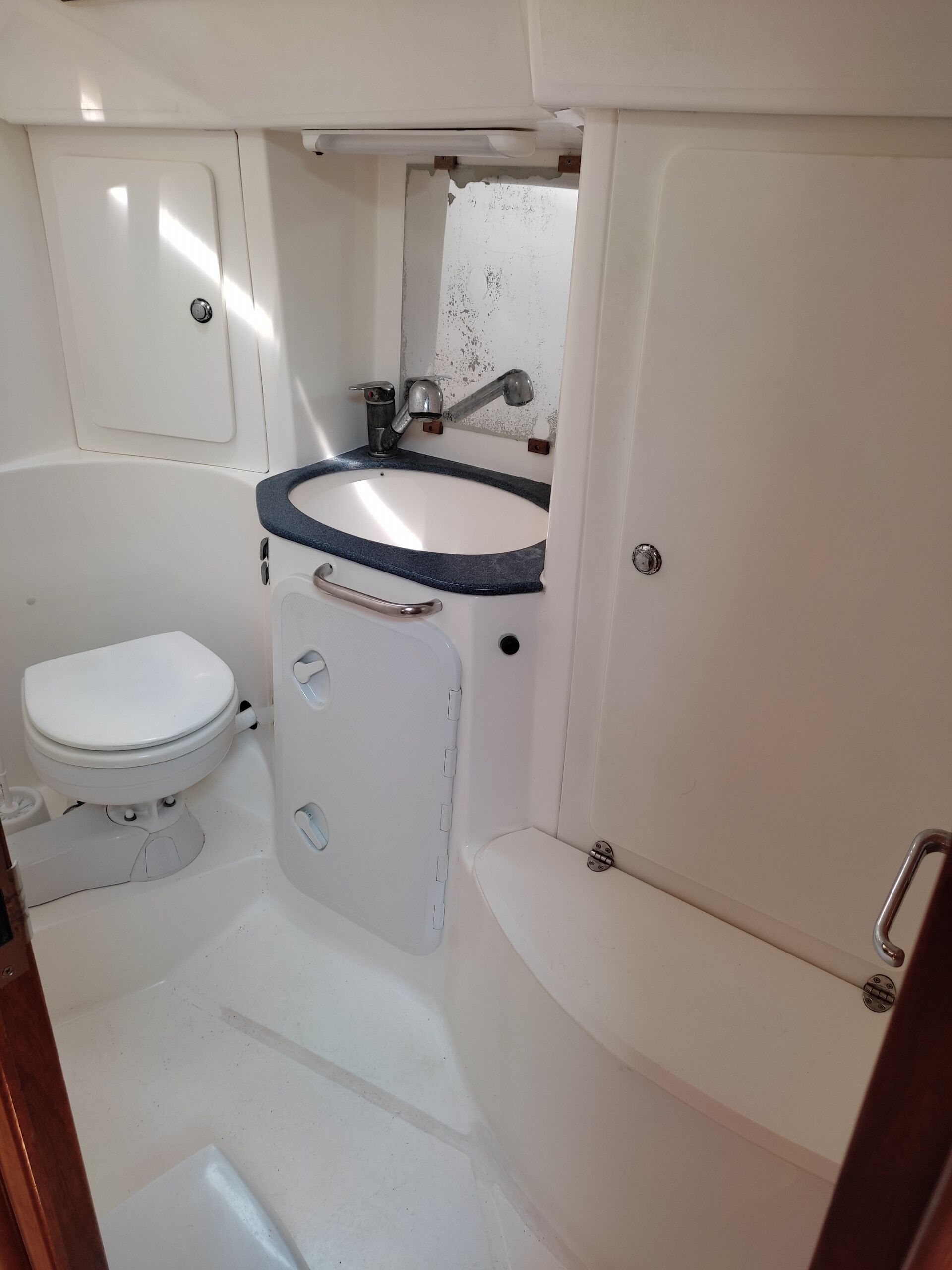 A compact bathroom with a white toilet, a sink with a blue rim, and a bathtub.
