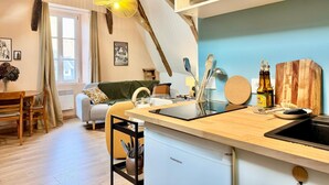 Una cocina moderna con una isla de madera, horno empotrado y zona de comedor con sofá y mesa.