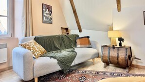 Una habitación acogedora con un sofá, un barril de madera y una alfombra estampada.