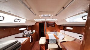 A compact interior with a dining area, seating, and a small kitchenette. - Sun-Kissed Sailing Adventure in Islas Sarónicas (Alimos)