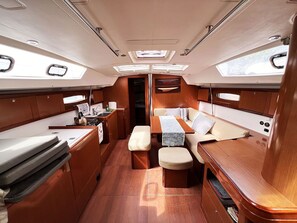 A compact interior with a dining area, seating, and a small kitchenette. - Sun-Kissed Sailing Adventure in Islas Sarónicas (Alimos)