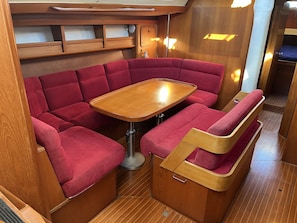 A compact, well-lit interior with a wooden table and red cushioned seating.