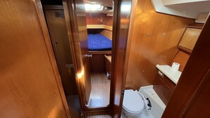 A compact, wood-finished interior with a small bed, a toilet, and a narrow passageway. - Sun-Kissed Sailing Adventure in Cataluña (Volos)