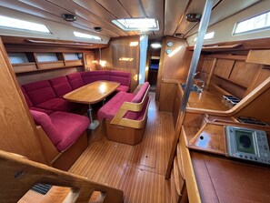 A compact interior with a dining table, cushioned seating, a small kitchenette, and a window.