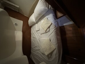 Ein Bett mit weißer Bettwäsche, einem Kopfteil und einer Holzwand.