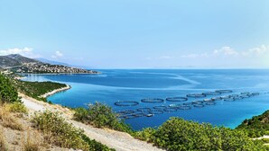 Paesaggio costiero con vista libera sul mare, una strada e una cittadina in lontananza.
