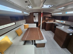 A compact galley with a central dining table, a small kitchenette, and a seating area with cushions.